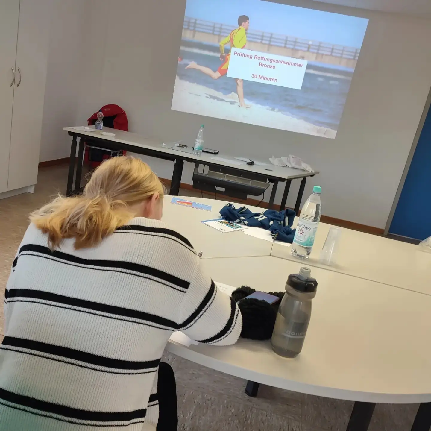 Schulungssituation: Personen sitzen vor einer Projektion bei einer DLRG-Ausbildung
